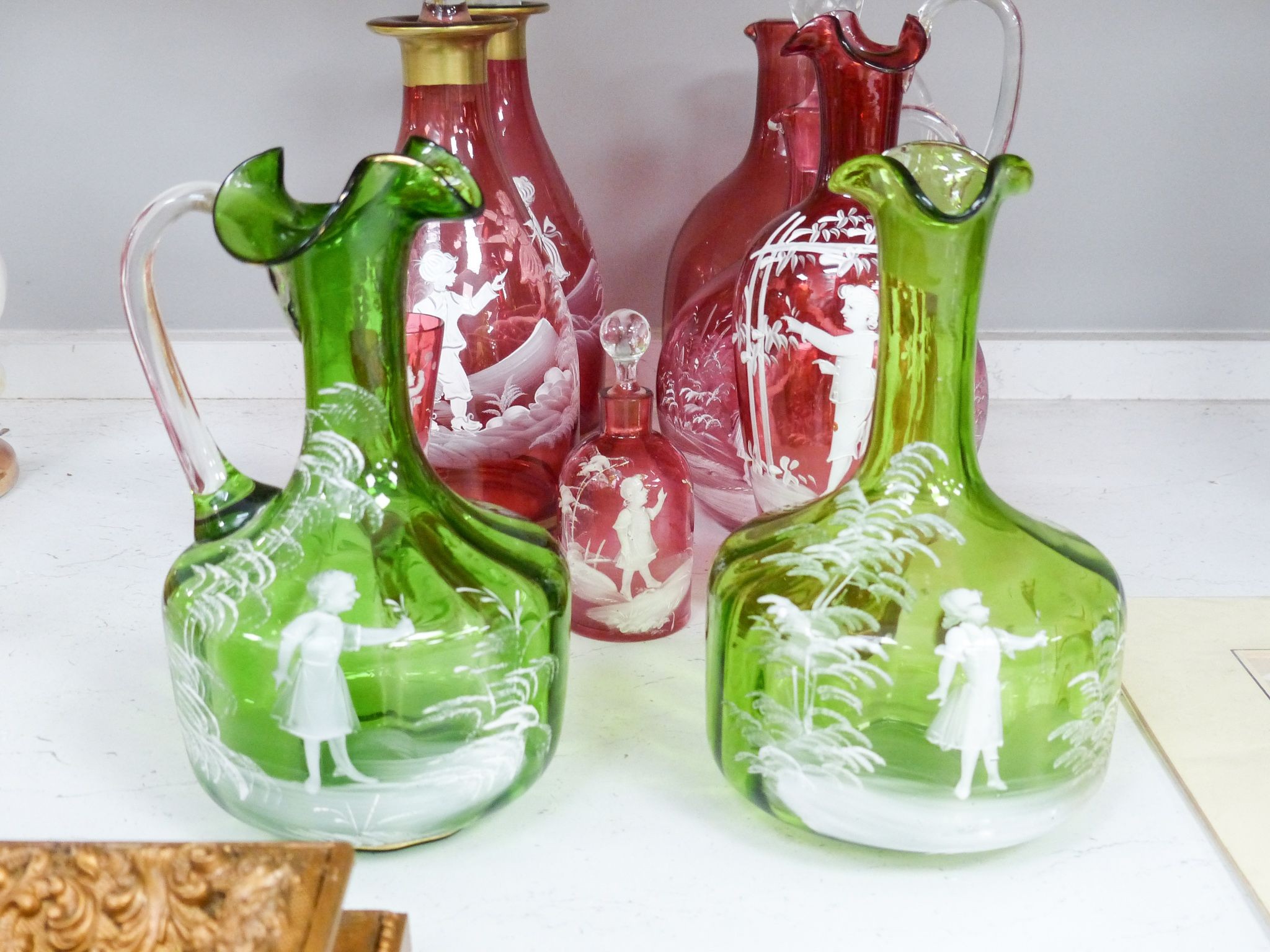 A collection of Mary Gregory cranberry and green glass decanters, jug etc (9), tallest 28.5 cm